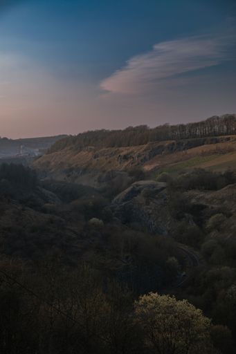 A vertical shot of a gorgeous landscape with vast hills and bushy trees under a bright sky