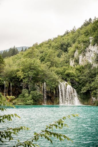 A vertical shot of a scenic waterfall with greenery in Plitvice Lakes National Park, Croatia