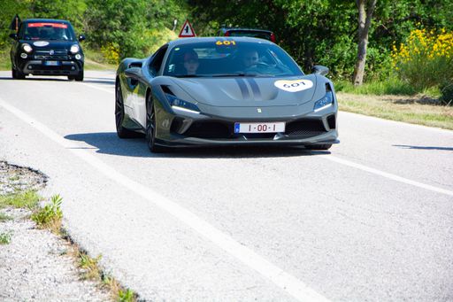 A black Ferrari F8 Tributo IN an old racing car in rally Mille Miglia 2022