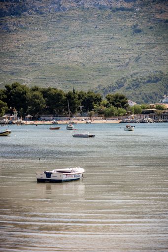 An aerial view of boats floating on lake in background of greenery mountain in Split