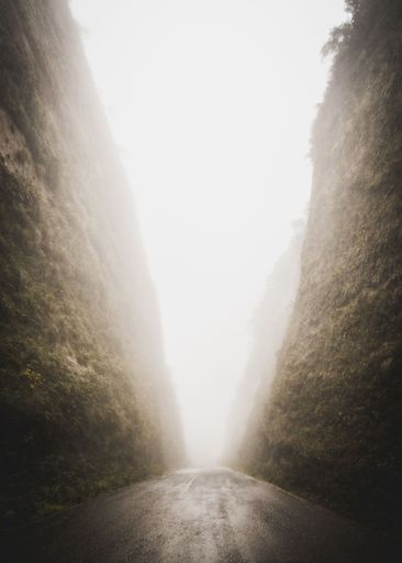 A beautiful shot of a narrow road surrounded by mountains covered with fog