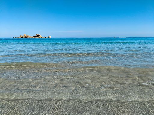 Beautiful beach with turquoise water and a rock in the background