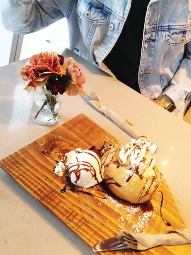 A vertical shot of delicious vanilla ice-cream next to bouquet of flowers on restaurant table