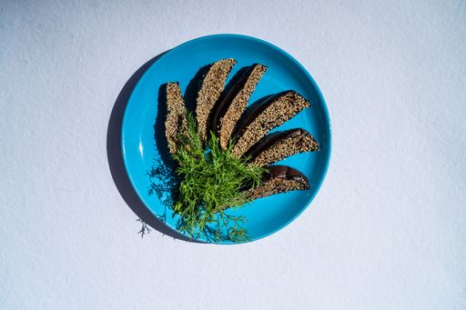 A top view of the oven-roasted eggplant wedges served on a blue plate and decorated with green dill