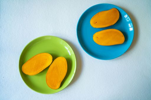 A top view of the tasty ripe mango slices on the blue and green plates