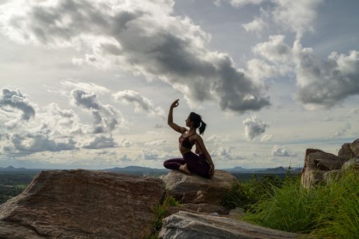 A young Indian female in sportswear doing yoga poses on a mountain