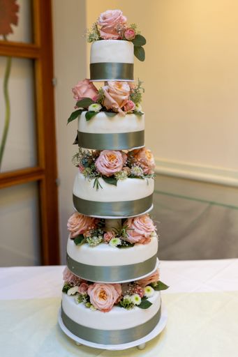 A vertical shot of a wedding cake decorated with flowers