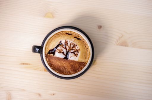 A Top view of a cup of Sunset tree latte art coffee on a wooden table
