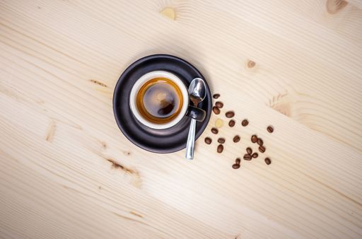 A Top view of a cup of coffee with coffee beans on a wooden table