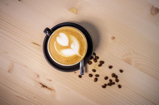 A top view of a freshly made cappuccino with coffee beans around