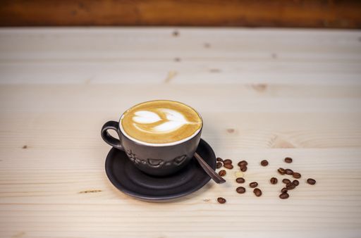 A freshly made cappuccino with coffee beans around