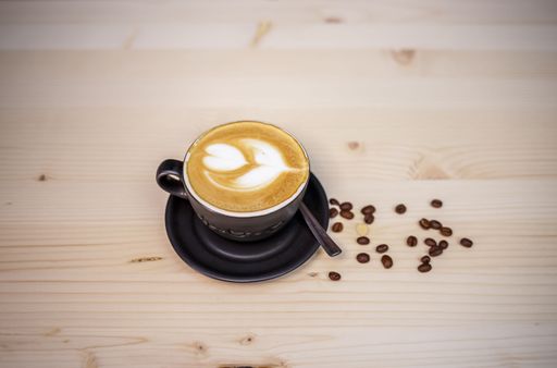 A closeup shot of a cup of a leaf-shaped coffee latte on a wooden table