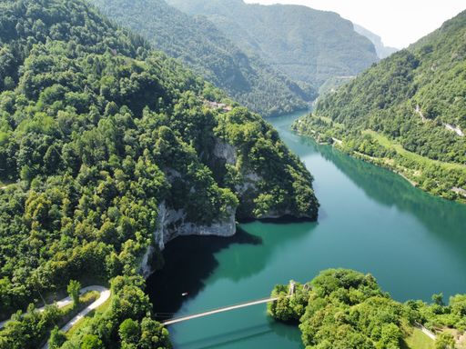A high angle shot of the lake Corlo in a valley surrounded by hills covered with forests