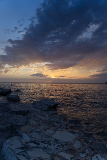 A vertical shot of a beautiful sunset sky over a rocky seashore