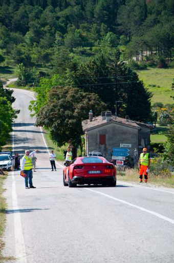 A vertical shot of the back of the red Ferrari 812 Superfast during the Mille Miglia 2022 with workers