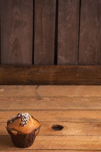 A vertical shot of a cupcake on a wooden surface