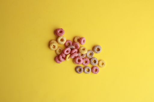 A high angle shot of some colorful fruit loops isolated on a yellow surface
