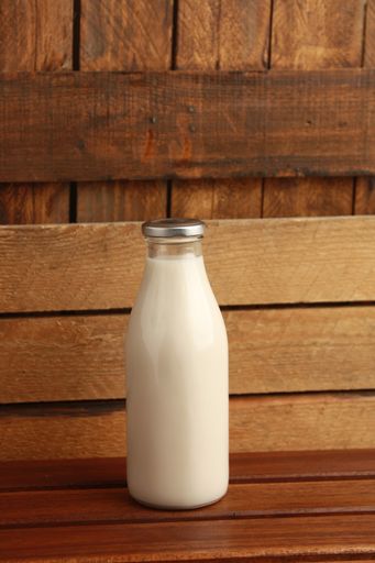 A vertical shot of a glass bottle of milk