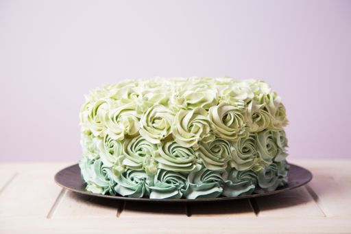 A selective focus shot of a beautifully decorated cake on a white wooden surface