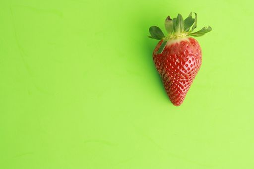 A top view of a whole strawberry on a green surface
