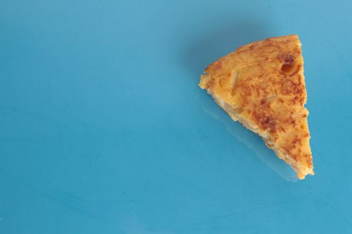 A high angle closeup shot of a piece of potato omelet skewer on a blue background