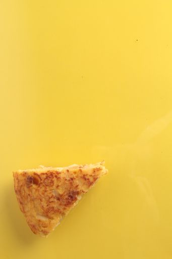 A top view of tasty Spanish omelet with potato on yellow background
