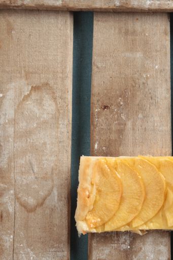 A vertical shot of a desert with slices of pear on a wooden surface