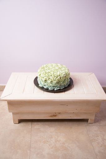 A vertical shot of a cake decorated with green roses from cream
