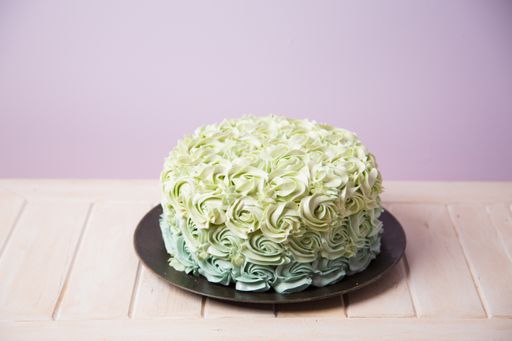 A closeup shot of a cake decorated with green roses from cream