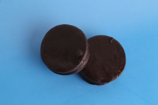 A top view of two chocolate biscuits with dulce de leche on a blue surface