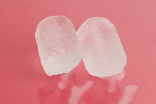 A high angle shot of two pieces of ice isolated on a pink surface
