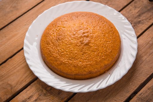 A closeup shot of freshly-made cake in a white plate on a wooden surface