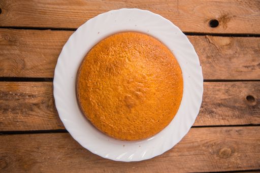 A closeup shot of freshly-made cake in a white plate on a wooden surface