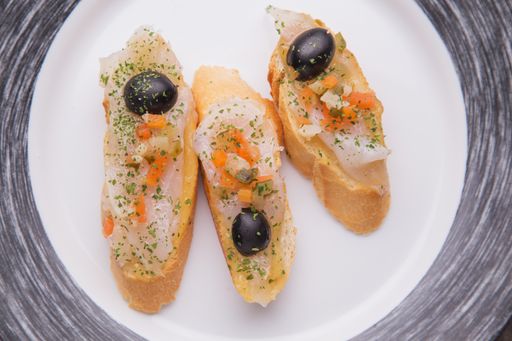 A top view of salmon and olives on bread slices in a plate