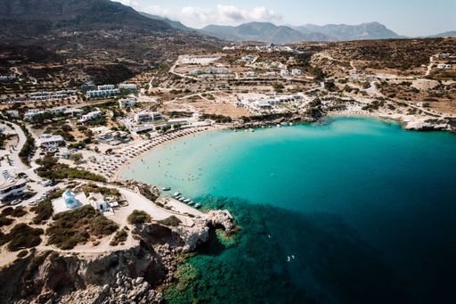 A aerial shot of the Amoopi Beach with white buildings and turquoise water, Karpathos, Greece