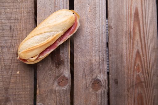 A closeup shot of a sandwich with ham on a wooden table