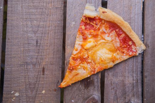 A top view of a slice of homemade pizza on a wooden table