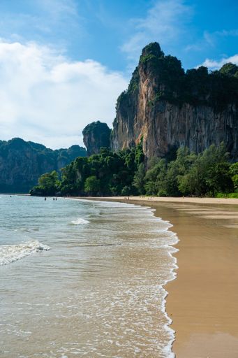 A vertical shot of a wavy beach with beautiful cliffs