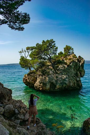 A vertical shot of a girl enjoying the view at Kamen Brela Rock Island, Croatia