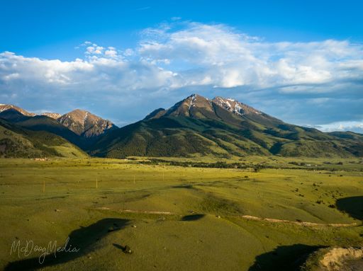 A gorgeous aerial view of tall mountains in the Paradise Valley in Montana under a bright cloudy sky
