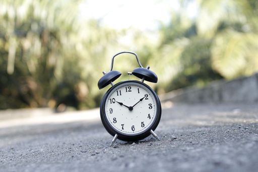 A close-up shot of an alarm clock placed on asphalt