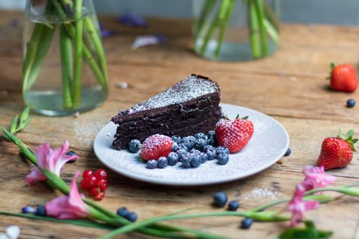 A closeup shot of a piece of brownie cake with blueberries and strawberries