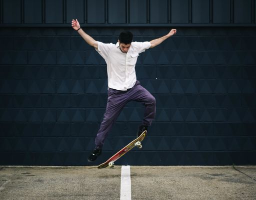 A young Caucasian man doing tricks with a skateboard at a skate park