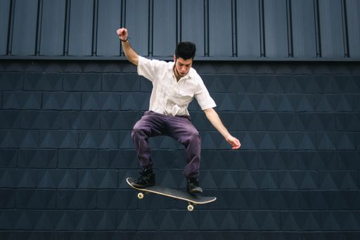 A young Caucasian man doing tricks with a skateboard at a skate park