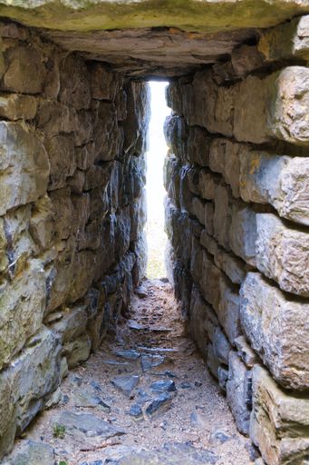 A vertical shot of brick stone walls making a narrow space with the light coming from