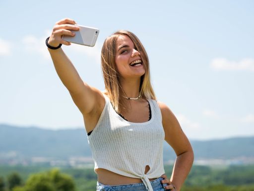 A shallow focus shot of a Caucasian female taking a selfie in nature