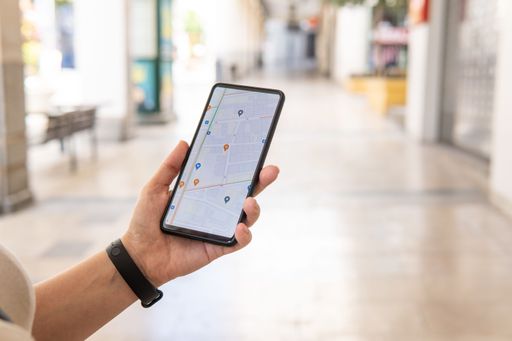 Woman hand with a smartphone searching on a map of the city for restaurants, places of interest, public transport. Various icons