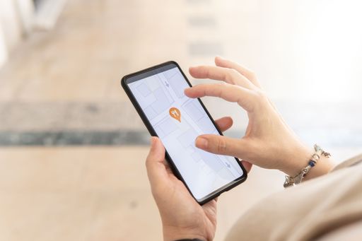 Woman hand with a smartphone searching on a map of the city for restaurants, places of interest, public transport. Various icons