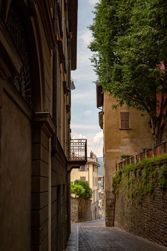 A vertical shot of cobblestone alley between medieval stone buildings in Bergamo, Italy