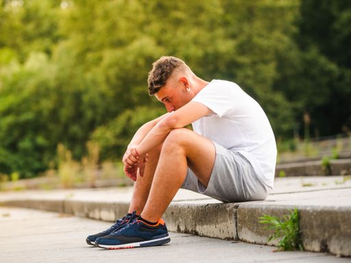 A young Caucasian man sitting on the stairs in the park